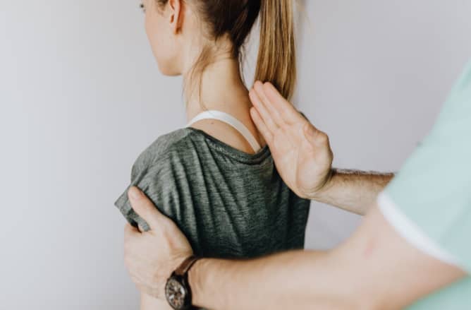 Crop anonymous chiropractor examining spine of fit lady